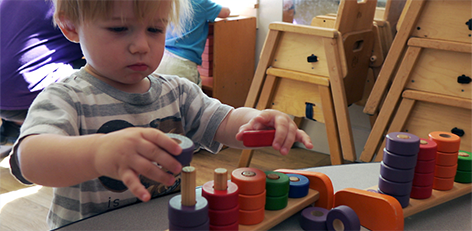 Little boy playing with wooden stacking toys